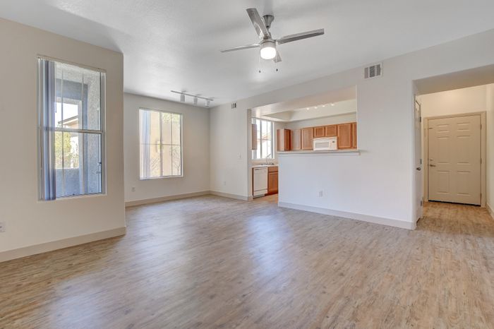 Bright open-concept living space with sleek wooden floors, modern kitchen with oak cabinetry, and ample natural light.