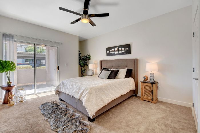 Bright and inviting bedroom featuring a plush bed with elegant decor, a cozy carpet, and a sliding glass door leading to a scenic view.