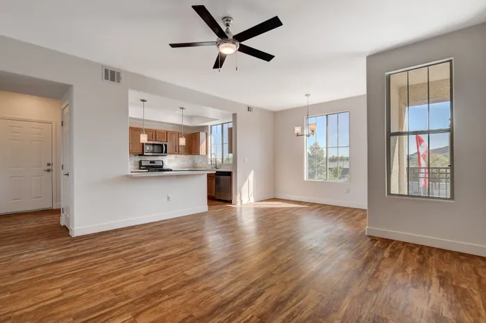 Bright and airy open-concept living space with elegant wood flooring, modern kitchen with stainless steel appliances, and large windows offering a scenic view.