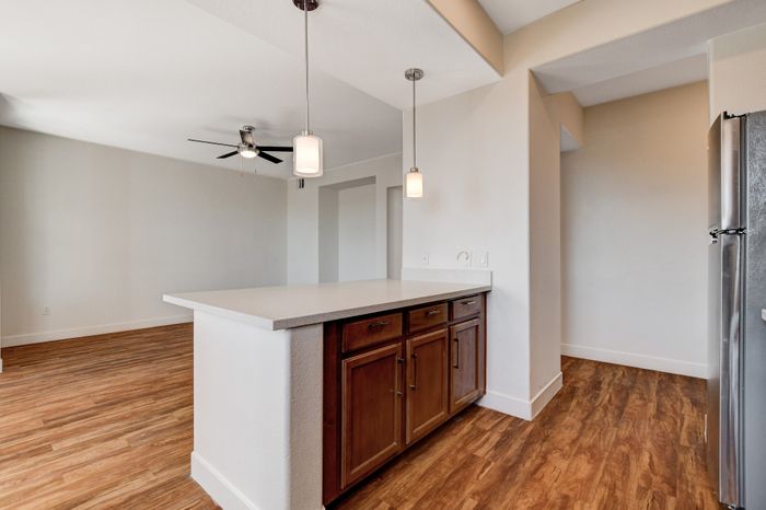 Modern apartment interior featuring an open-concept kitchen with a stylish island, pendant lighting, and elegant wood flooring.