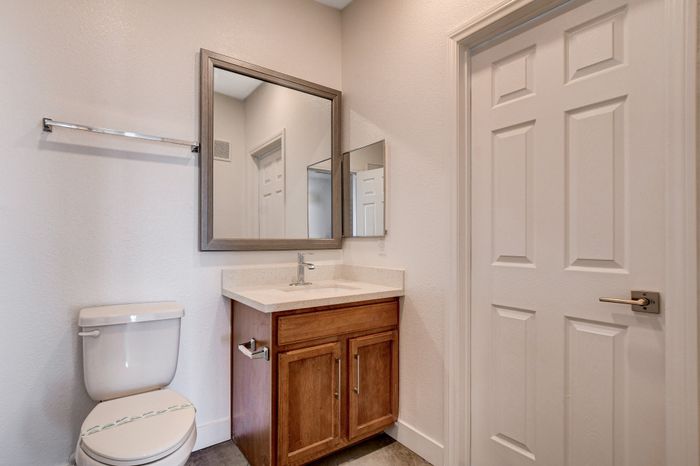 Modern bathroom featuring a sleek vanity with wooden cabinets, a large mirror, and contemporary fixtures.