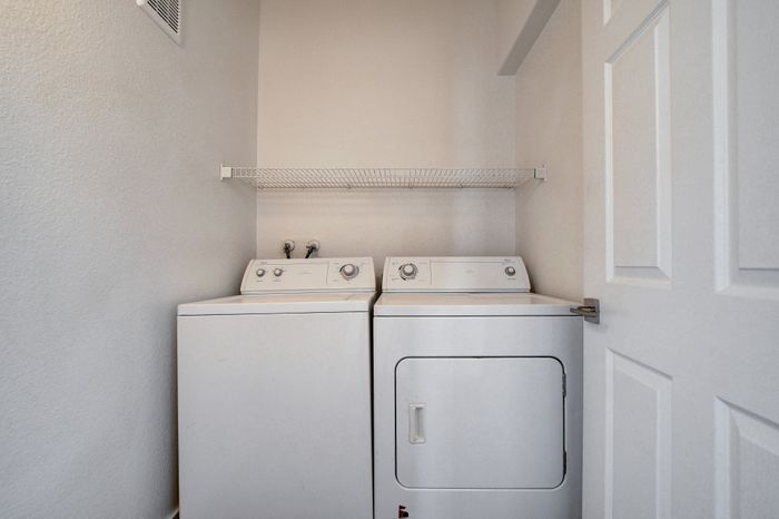 Convenient in-unit laundry with washer and dryer, featuring a sleek design and extra storage shelf.
