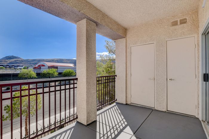 Charming balcony with open views of distant hills and a school, featuring a modern design and ample sunlight.
