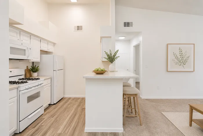 Bright and modern kitchen with sleek white cabinetry, breakfast bar, and cozy seating in an elegant open-concept design.