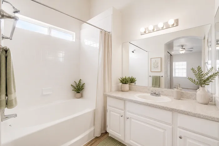 Bright and inviting bathroom with modern white fittings, spacious countertop, and elegant greenery accents.