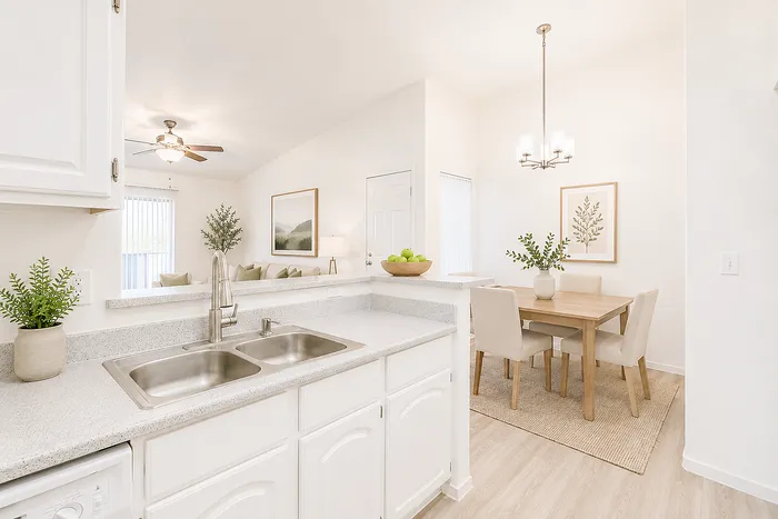 Bright and airy kitchen with sleek countertops, adjacent to a cozy dining area accented with modern decor.