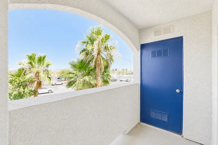 Charming balcony with vibrant blue door and stunning palm tree view, offering a warm and inviting outdoor space.