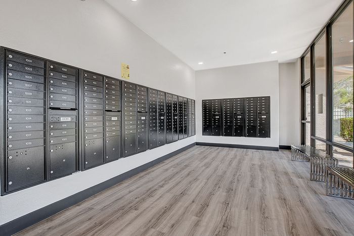 Modern apartment lobby with sleek black mailboxes, natural light, and stylish wooden flooring.