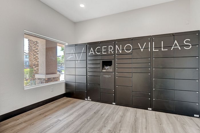 Modern parcel locker area with sleek black lockers, natural light flooding through large windows, and stylish wood flooring at Acerno Villas.