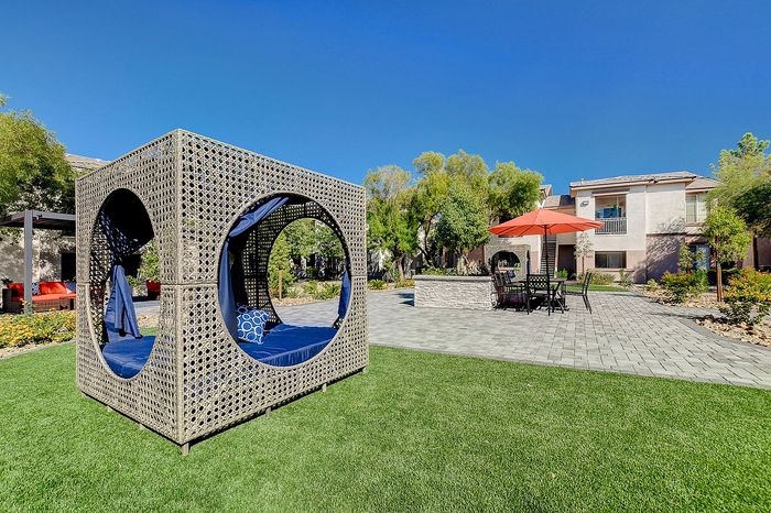 Charming apartment courtyard with a stylish outdoor seating area, modern lounge furniture, and vibrant garden under a clear blue sky.