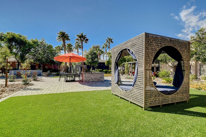 Luxurious outdoor lounge area with stylish modern seating, vibrant green lawn, and elegant patio with palm trees.