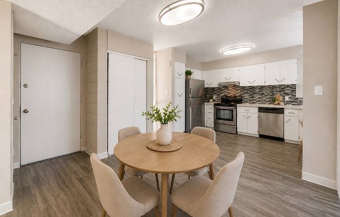 Contemporary apartment interior with a modern kitchen featuring sleek stainless steel appliances and a stylish dining area with warm wood accents.