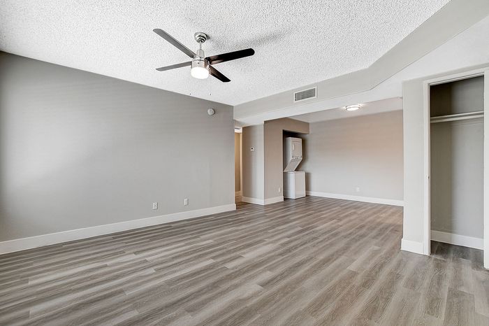 Modern living space with sleek ceiling fan, elegant wood flooring, and built-in laundry for convenience.