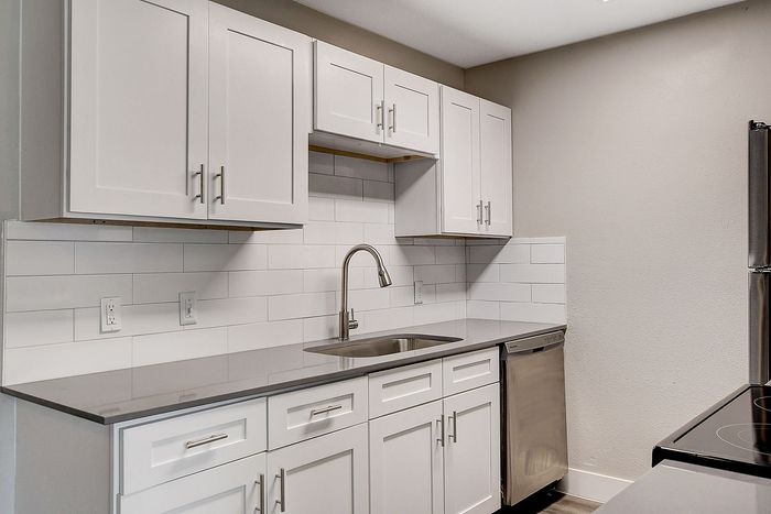 Modern kitchen with sleek white cabinetry, stainless steel appliances, and elegant tile backsplash.