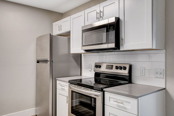 Modern kitchen with sleek stainless steel appliances, white cabinetry, and a contemporary backsplash.