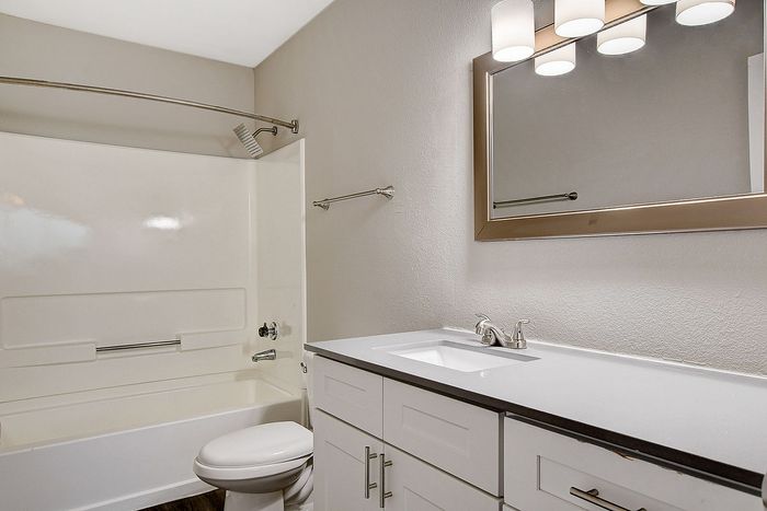 Modern bathroom featuring a sleek vanity, elegant mirror, and pristine bathtub with chrome fixtures.