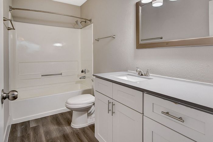 Modern bathroom design with sleek white cabinetry, elegant countertop, and a pristine bathtub.