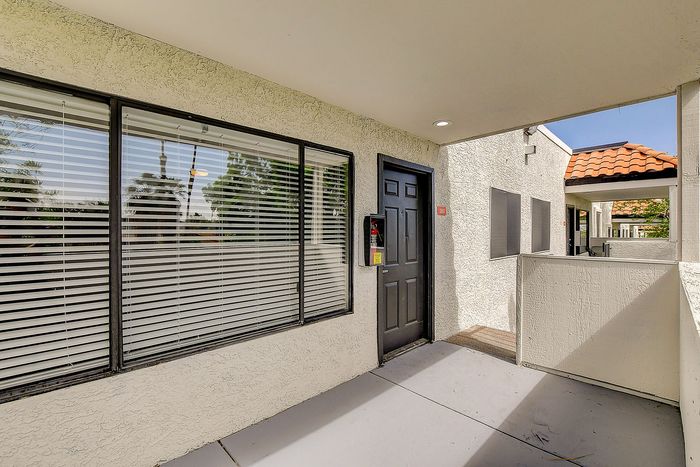 Charming apartment entrance with a sleek black door and expansive windows, offering a glimpse of lush greenery outside.