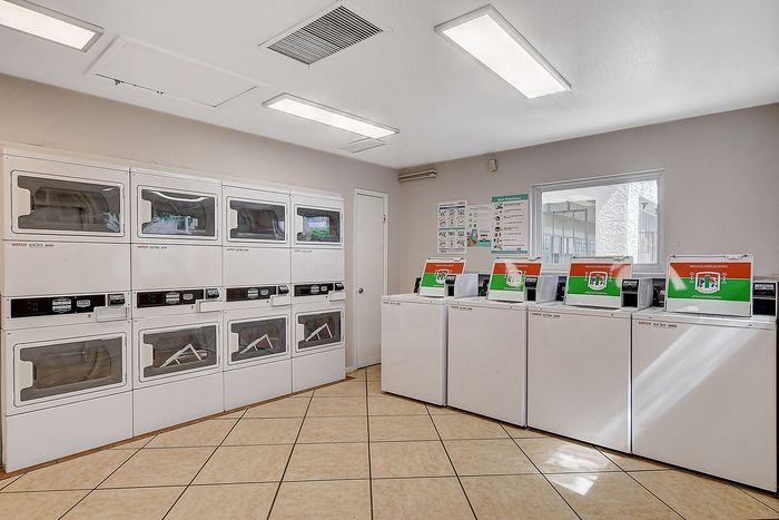 Modern laundry facility featuring multiple washers and dryers, enhanced by ample lighting and a clean, spacious layout.