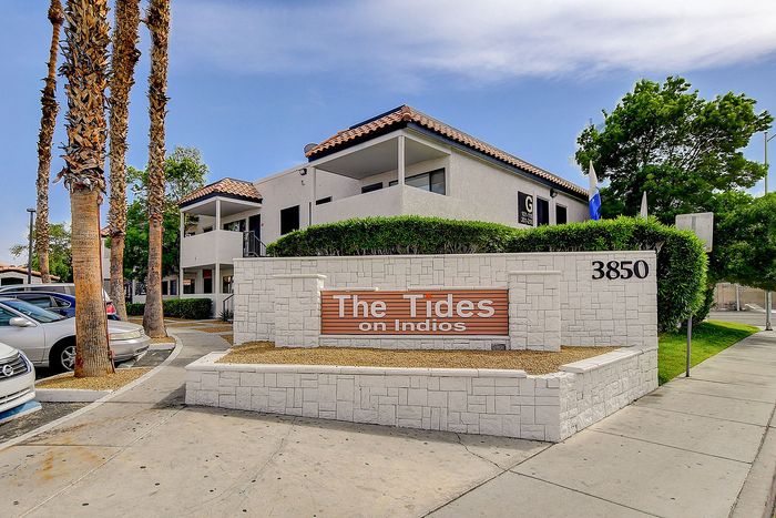 Inviting exterior of The Tides on Indios, showcasing modern architecture with lush greenery and palm trees, perfect for sophisticated living.