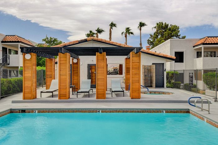 Inviting outdoor swimming pool with modern wooden cabanas and stylish lounge chairs, set against a backdrop of elegant architecture and lush greenery.