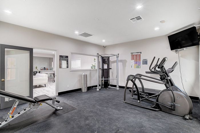 Modern fitness center featuring state-of-the-art exercise equipment, flat-screen TV, and a refreshing open space design.
