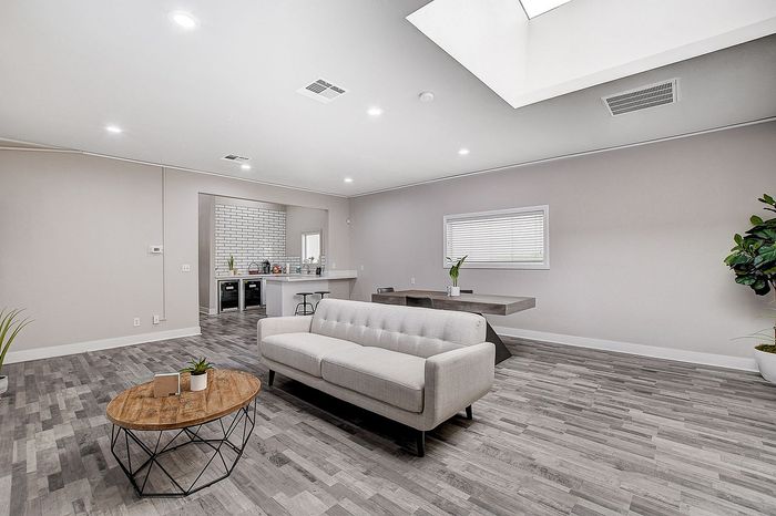 Modern open-concept living area featuring elegant gray wood flooring, a cozy sofa, and a stylish kitchen with a breakfast bar.