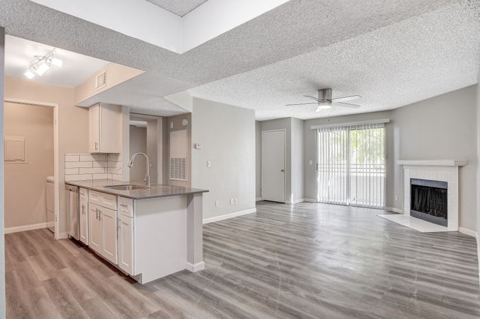 Spacious open-concept living area with modern kitchen, natural light, and chic fireplace.