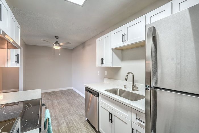 Modern kitchen with sleek stainless steel appliances, elegant white cabinetry, and a spacious layout enhanced by a stylish ceiling fan.