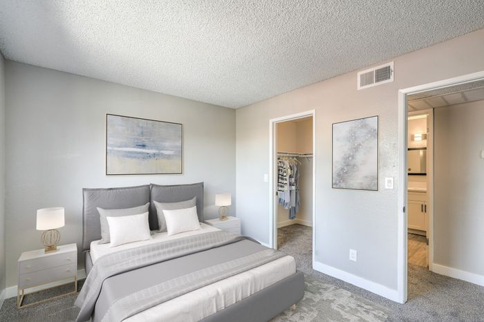 Modern bedroom with cozy gray bedding, elegant nightstands, and spacious walk-in closet.