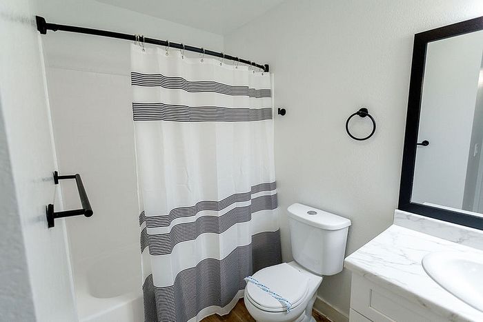 Bright and modern bathroom featuring sleek fixtures, a striped shower curtain, and elegant marble countertop.