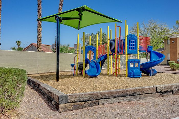 Charming outdoor playground with vibrant blue and yellow equipment, featuring a slide and climbing structures, ideal for family fun and relaxation.