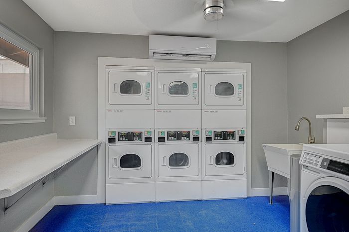 Modern laundry room with stacked washer-dryer units, a spacious folding area, and a convenient utility sink.