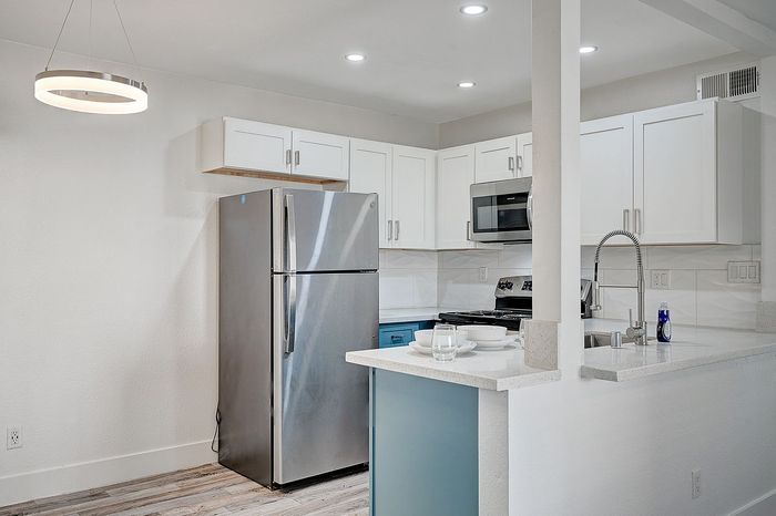 Modern kitchen featuring sleek stainless steel appliances, elegant white cabinetry, and a stylish breakfast bar.