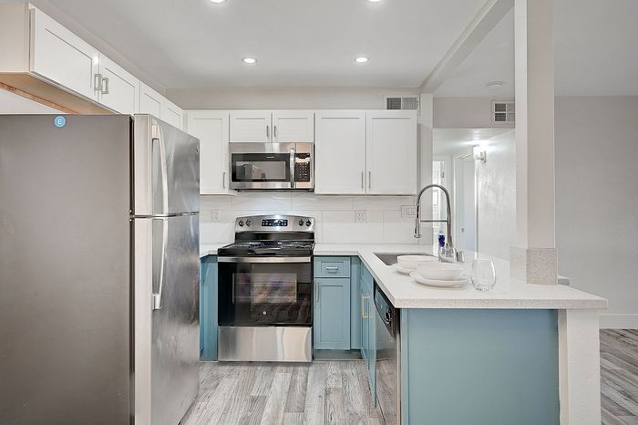 Modern kitchen with sleek stainless steel appliances, elegant white cabinetry, and a stylish blue accent island.