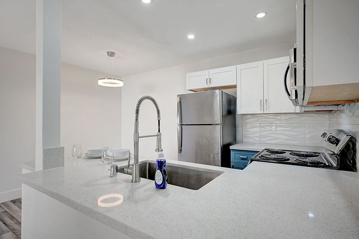 Modern kitchen with sleek stainless steel appliances, elegant white cabinetry, and a stylish quartz countertop.