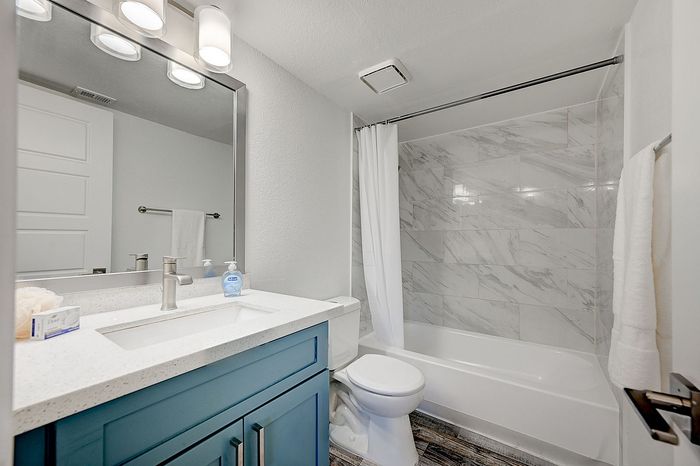Modern bathroom with elegant marble tile shower, sleek vanity, and contemporary fixtures.