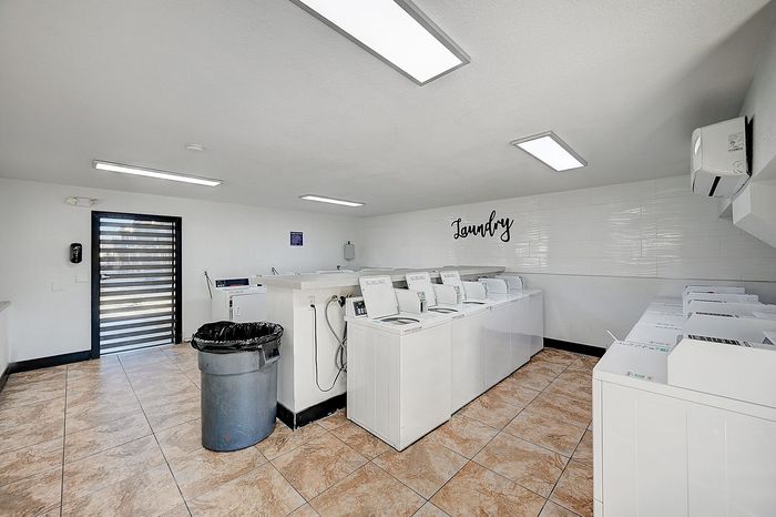 Bright and spacious laundry room featuring modern washing machines and tiled flooring, ideal for convenient apartment living.