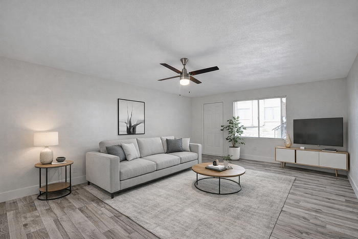 Modern living room with stylish gray sofa, sleek wooden flooring, and contemporary decor including a ceiling fan and large window.