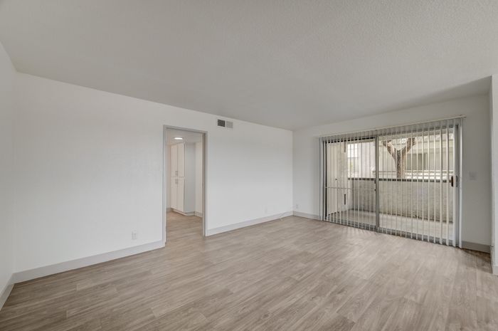 Bright and spacious living room with elegant hardwood flooring and large sliding glass doors leading to a balcony.
