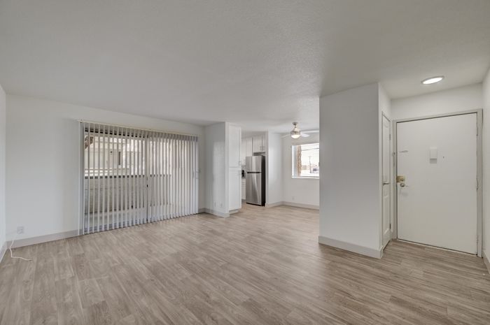 Bright and spacious apartment interior with hardwood floors, modern kitchen, and abundant natural light through large windows.