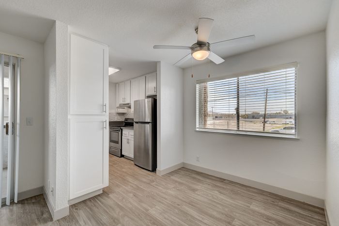 Bright apartment kitchen with modern stainless steel appliances, sleek cabinetry, large window, and stylish ceiling fan.