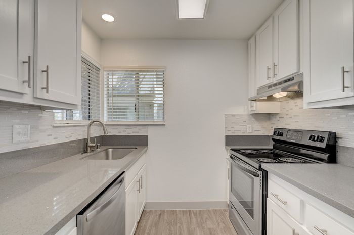 Modern kitchen with sleek countertops, stainless steel appliances, and ample natural light from large windows.