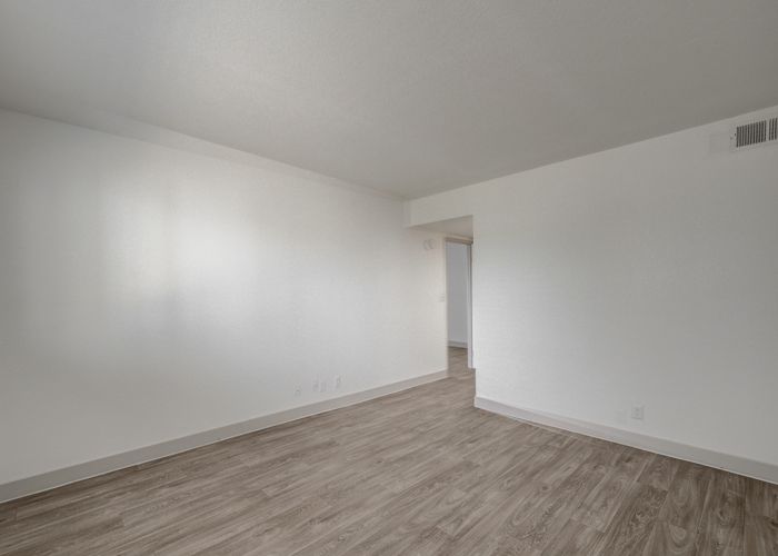 Spacious living area with elegant wood flooring and fresh white walls, ideal for modern interior design.