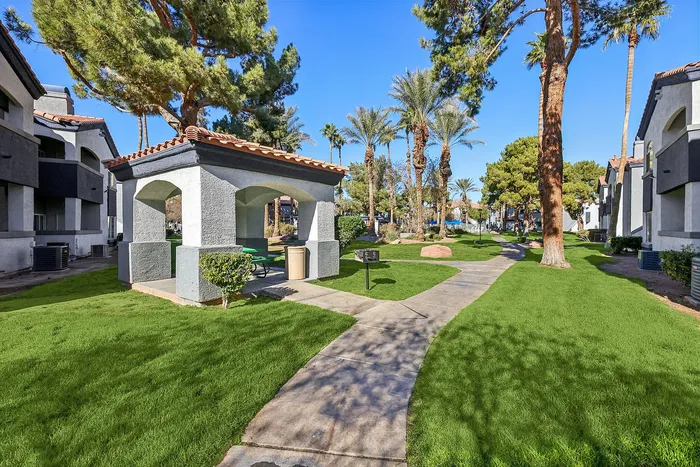 Charming community courtyard with lush greenery, palm trees, and a cozy gazebo, perfect for relaxation and leisure.