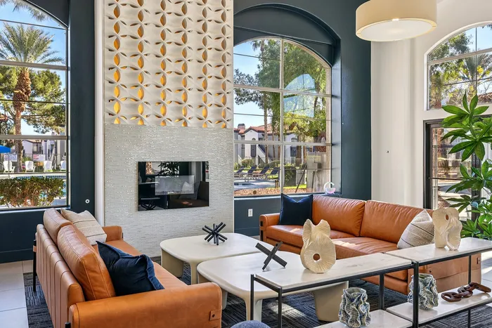 Chic living room with modern leather sofas, elegant decor, and expansive windows offering a view of lush greenery.