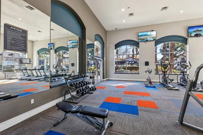 Bright and modern fitness center equipped with treadmills, stationary bikes, and ample weights, featuring large windows with scenic views.