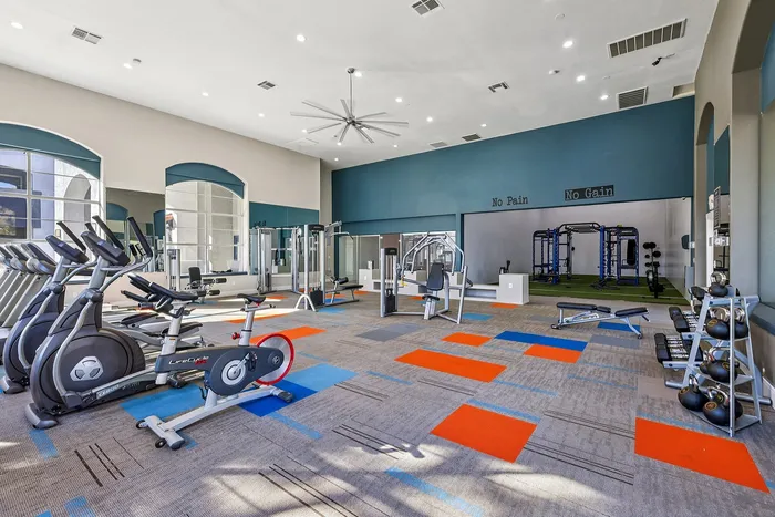 Modern fitness center with state-of-the-art cardio machines, weight equipment, and vibrant flooring, offering an invigorating atmosphere for workouts.