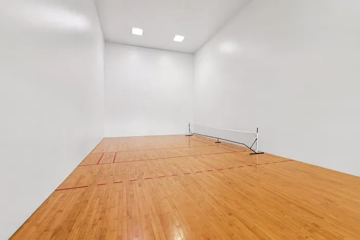 Bright and spacious indoor squash court with polished wooden floors and pristine white walls.