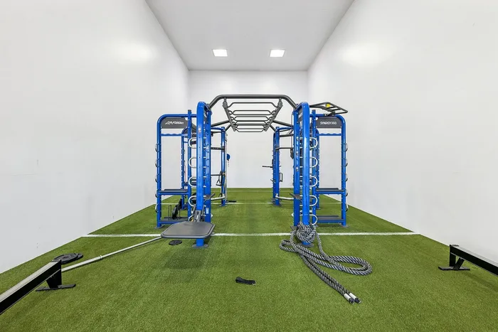 Modern gym facility with advanced blue fitness equipment and artificial turf flooring, perfect for dynamic workouts.